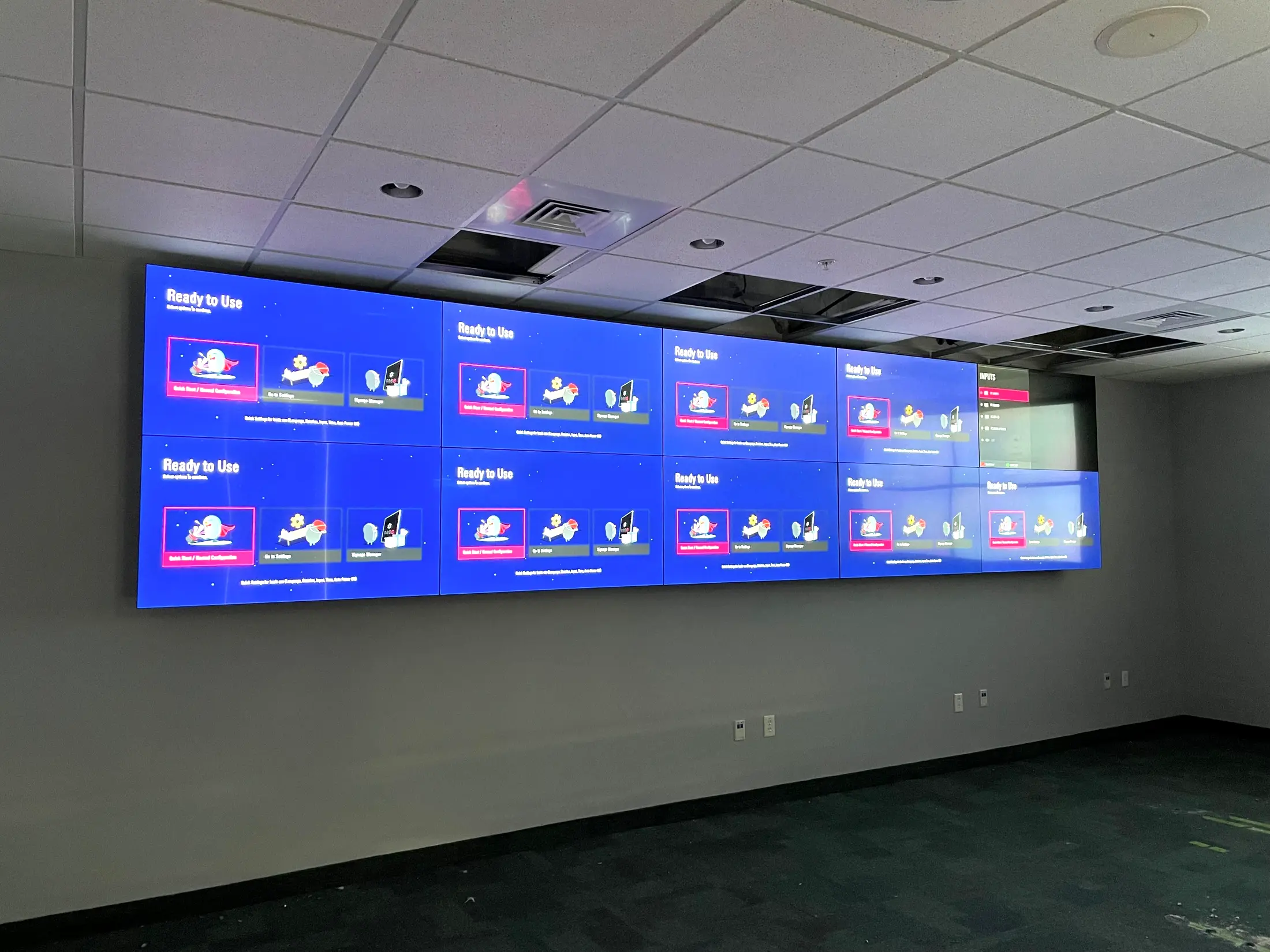 A ten panel video wall lit up on the wall of a darkened room, showing the display setup screen before content is loaded.